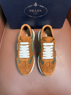 Unisex Prada sneakers in tan suede with green panels, white laces and rubber sole.