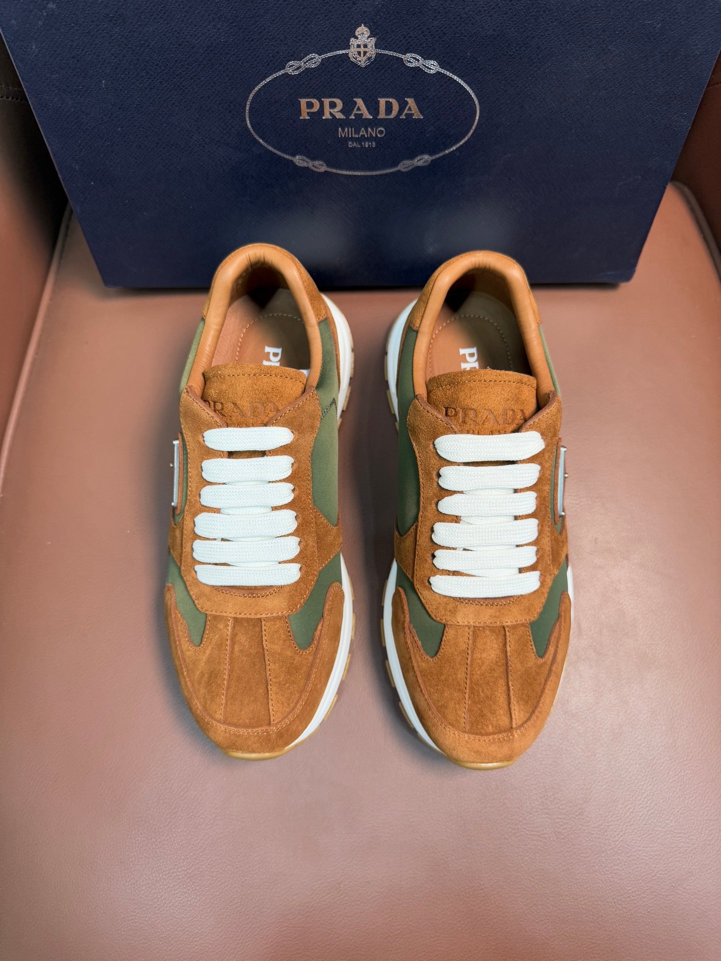 Unisex Prada sneakers in tan suede with green panels, white laces and rubber sole.