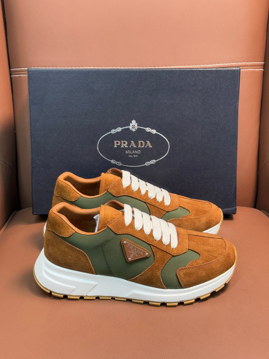 Unisex Prada sneakers in tan and green colorblock suede with white laces and sole.