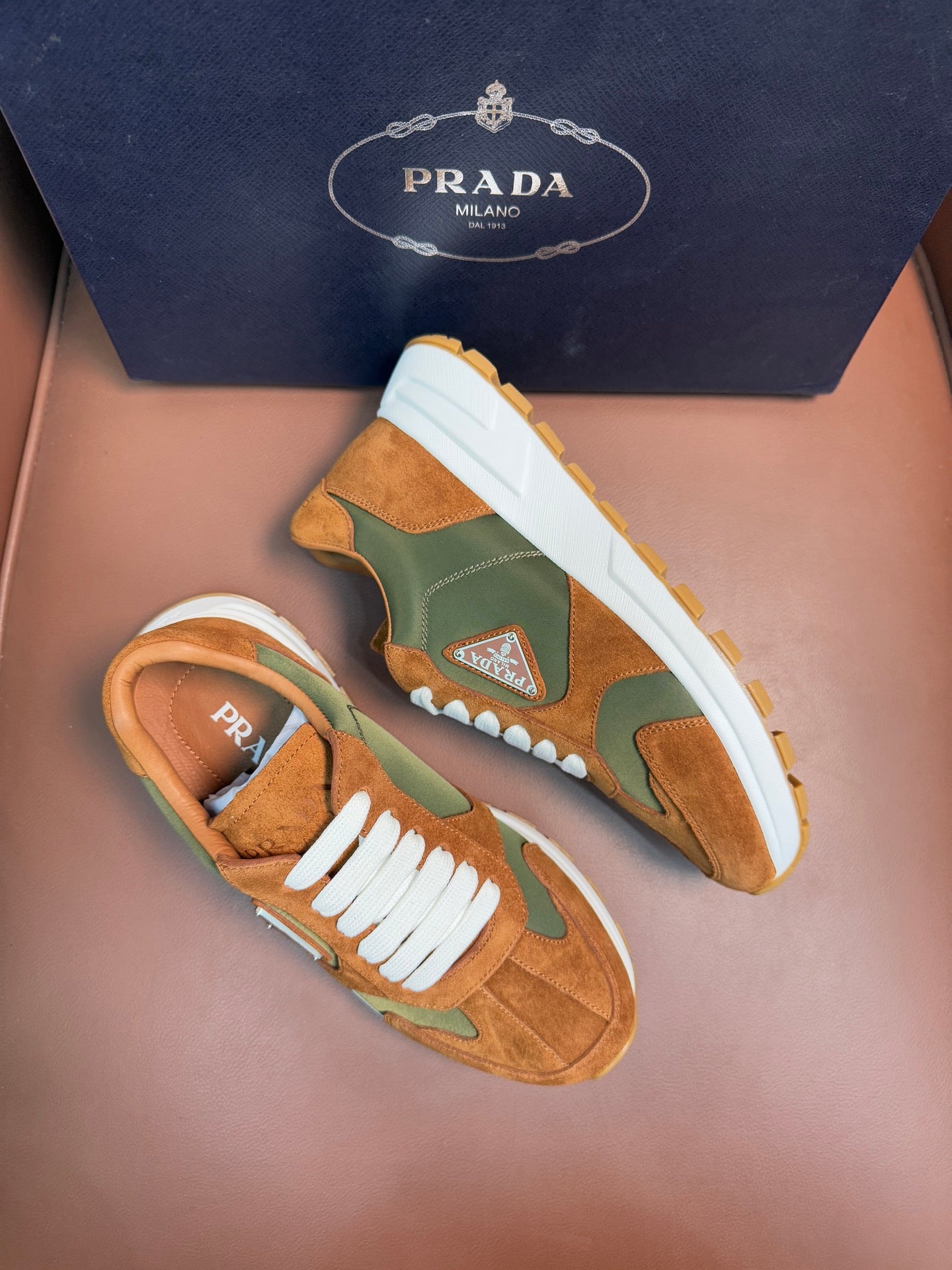 Unisex Prada low-top sneakers, tan and green colorblock with white laces and thick sole.