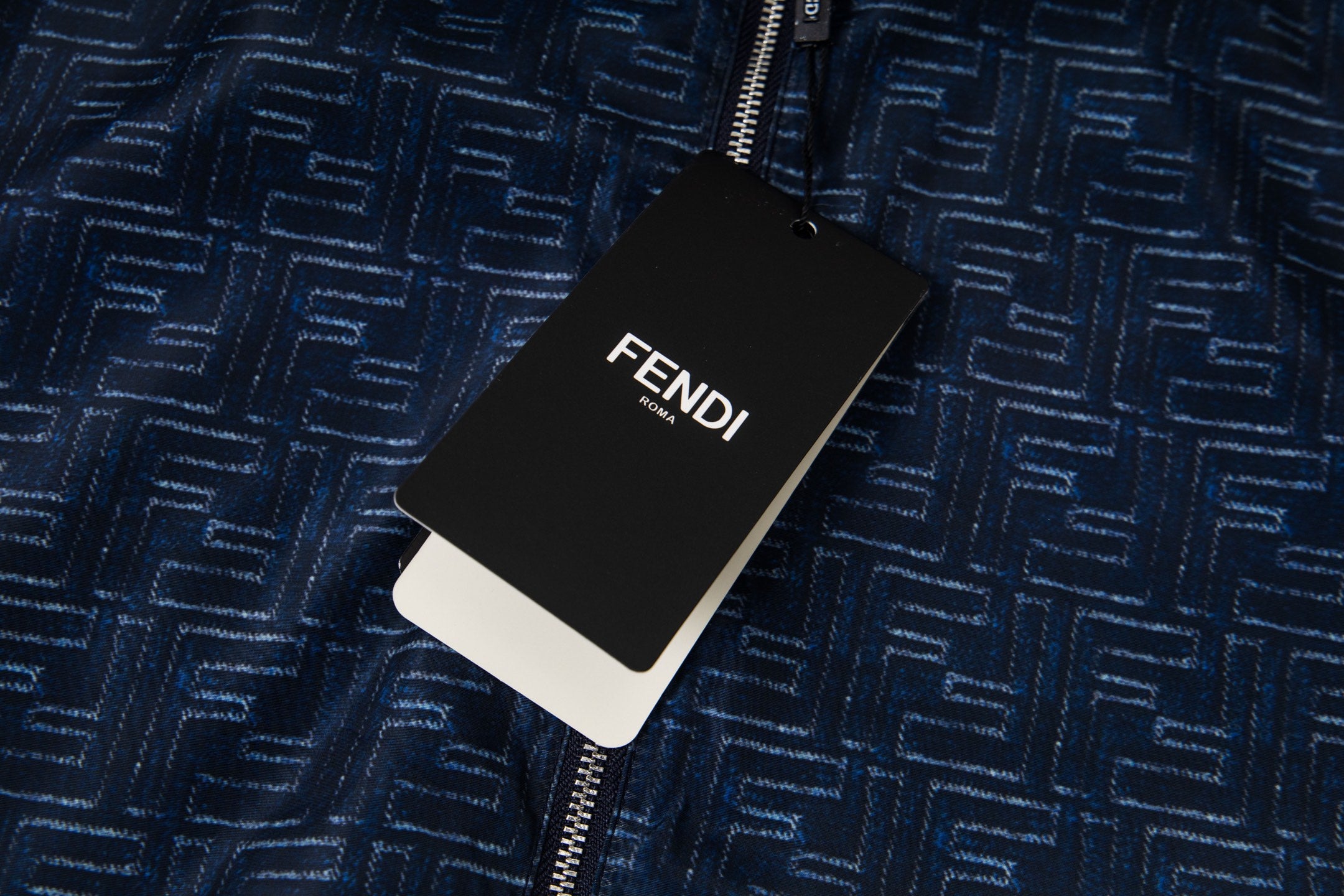 FENDI brand label tag on navy zip-up jacket with geometric pattern