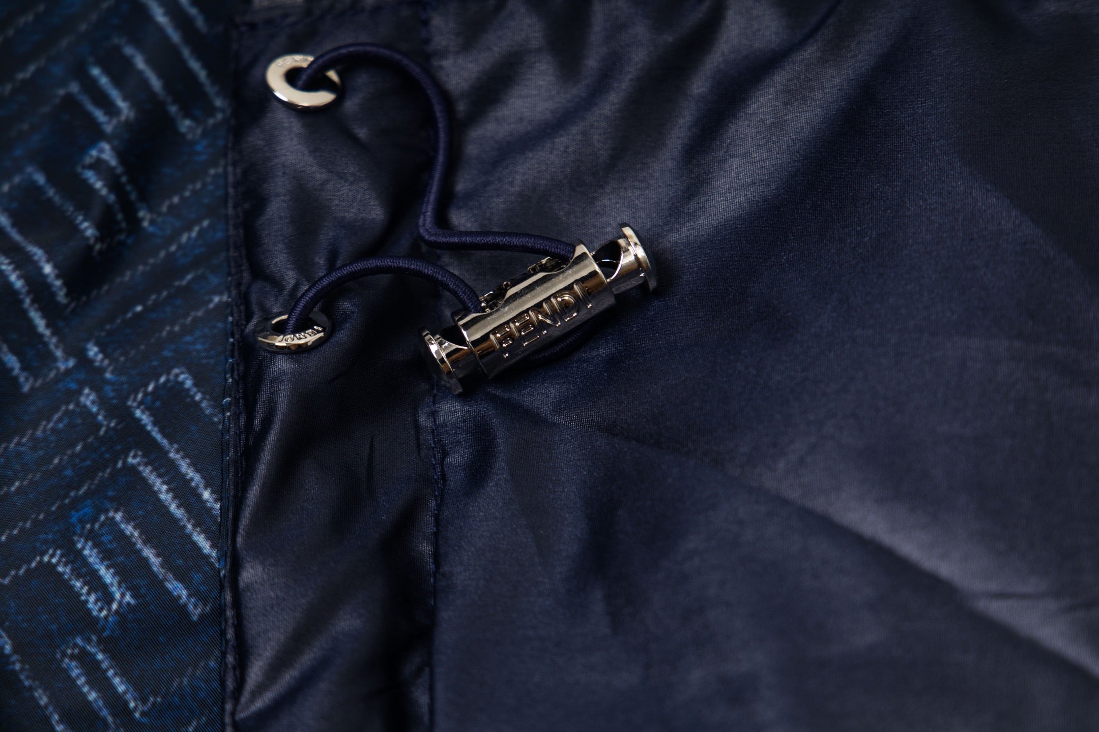 Navy jacket front with snap and zipper pull, metal logo tab