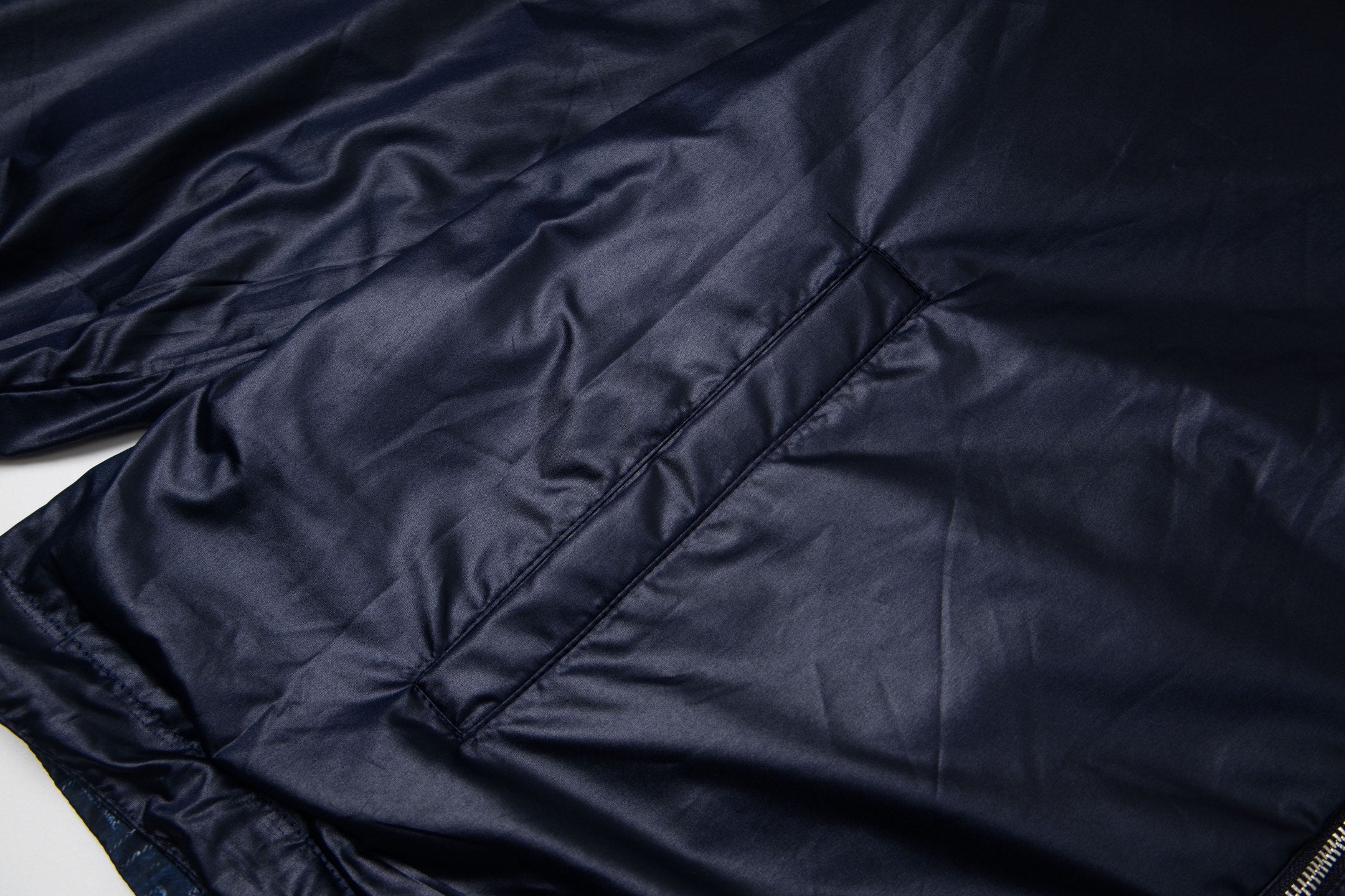Navy hooded jacket with diamond quilting stitch detail and diagonal paneling