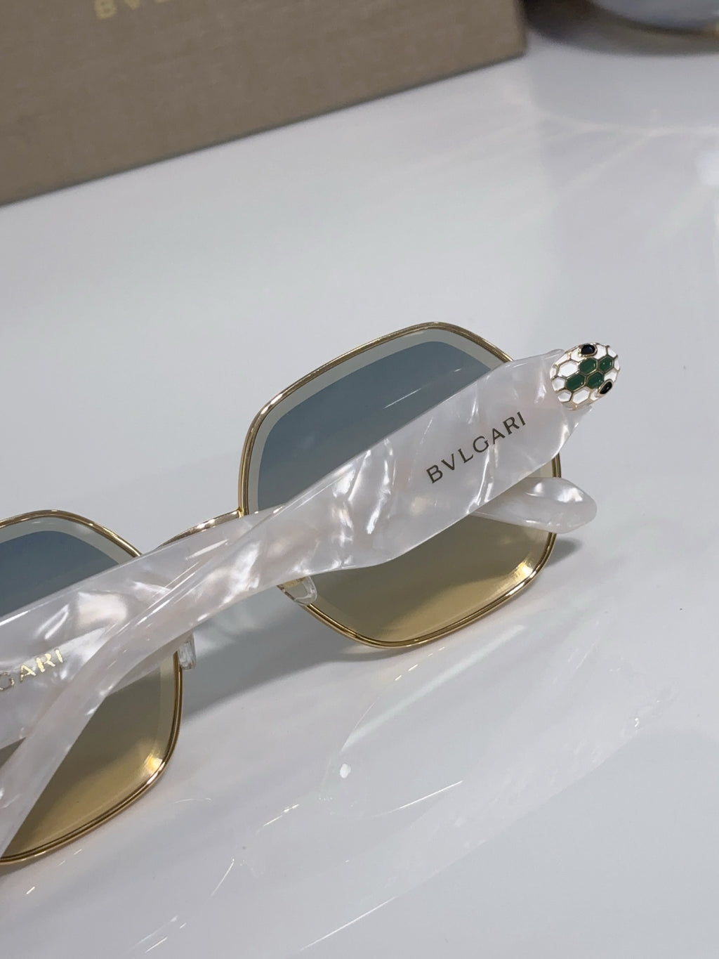Gold sunglasses arm with green jewel detail and BVLGARI logo on temple