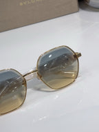 Gold-rim sunglasses with dark blue lens and round frame profile