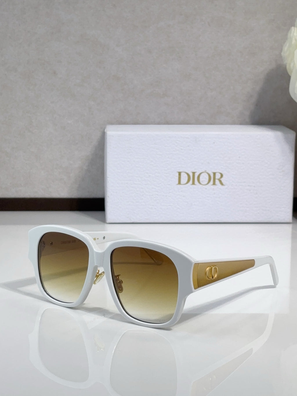 Dior sunglasses, white frame with amber-tinted lenses and gold logo detail