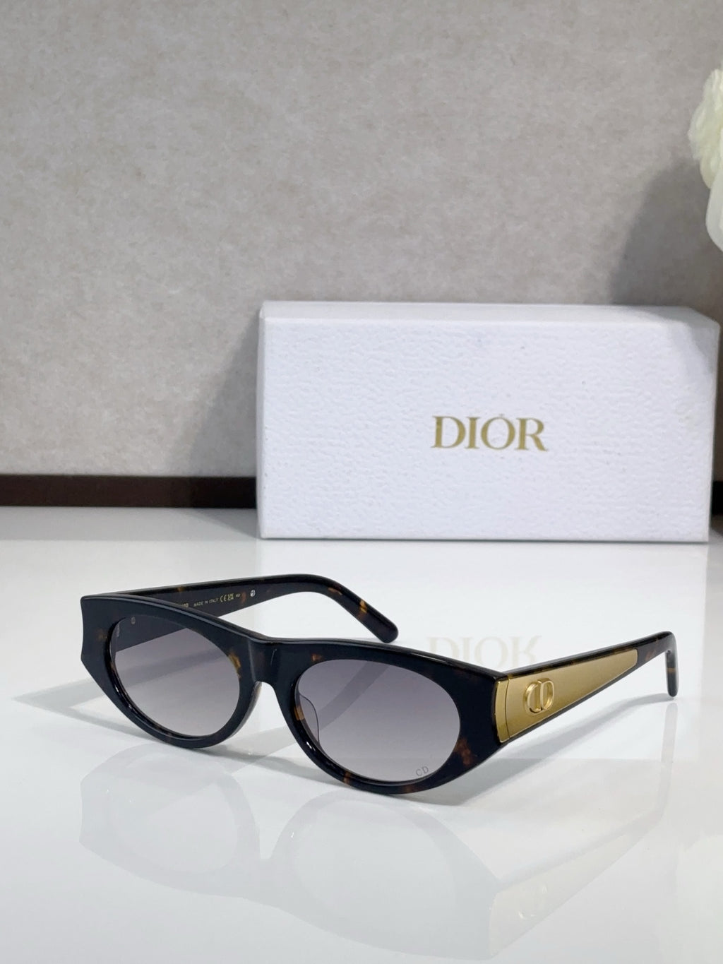 Dior sunglasses, dark frames with gold logo temples and clear-lens gradient tint