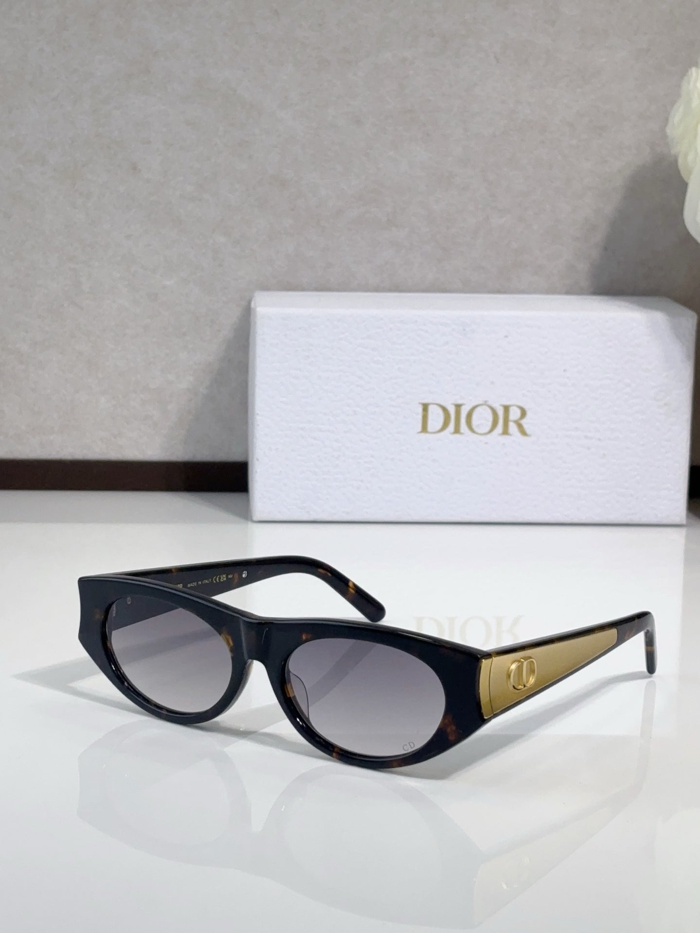 Dior sunglasses, dark frames with gold logo temples and clear-lens gradient tint