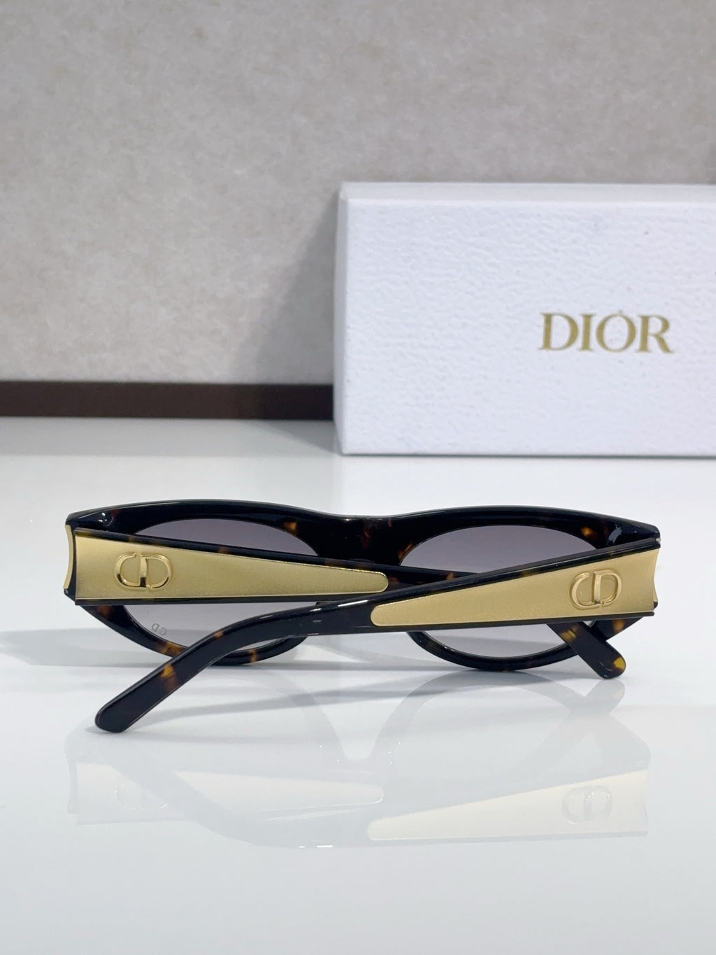 Dior sunglasses, dark frames with gold logo accents and tinted lenses