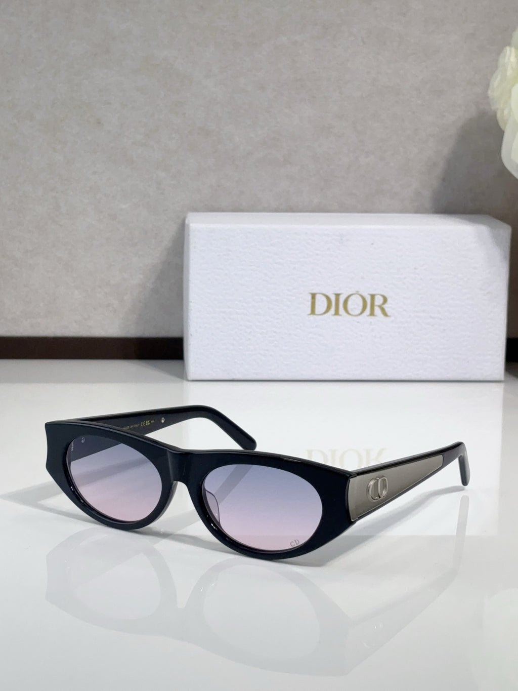 Dior sunglasses, black frames with gold logo temples and pink-tinted lenses