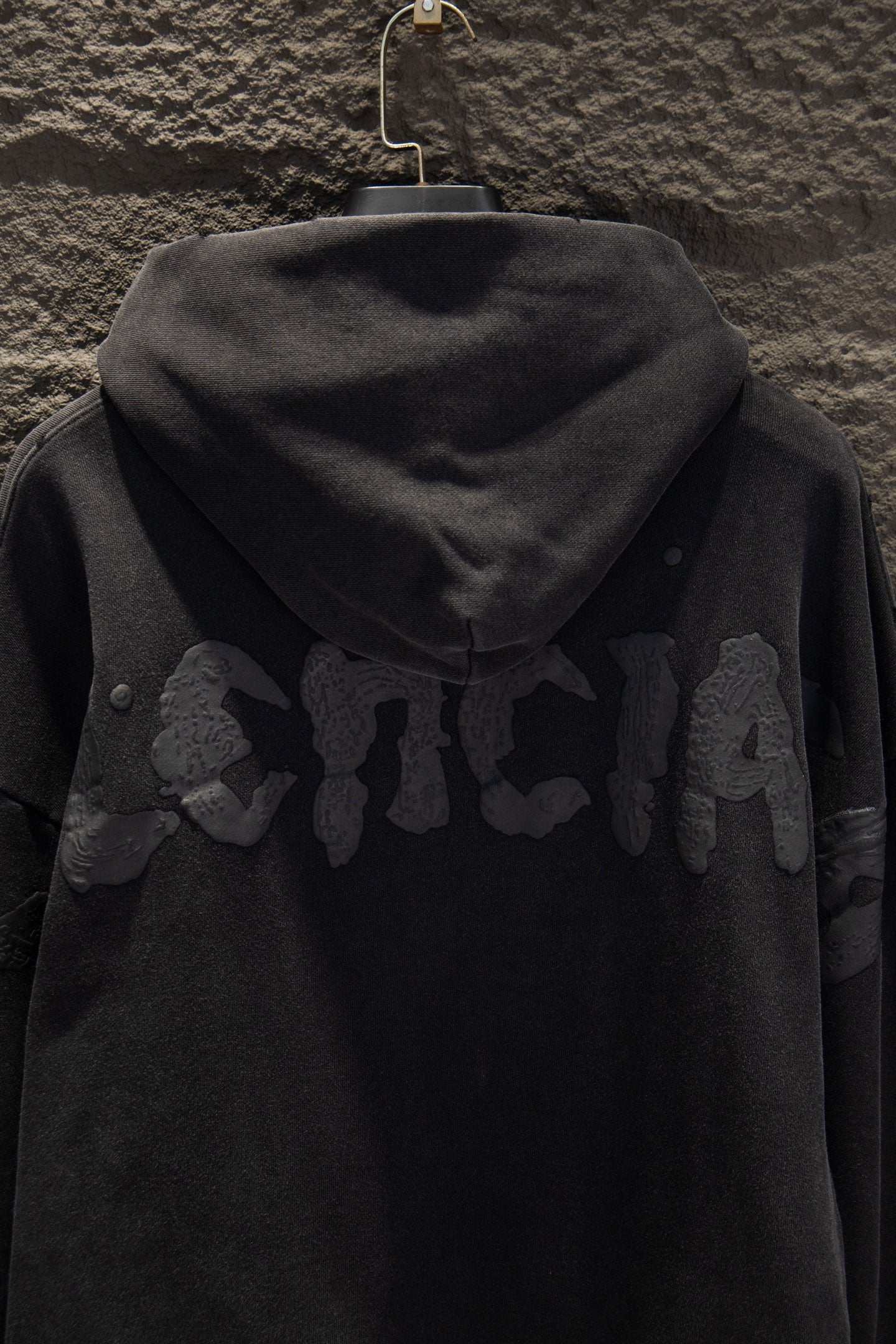 Balenciaga long zip-up hoodie back view, dark with hood and raised graphic lettering.
