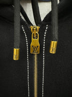 Close-up of gold zipper pull and LV emblem on a black hoodie