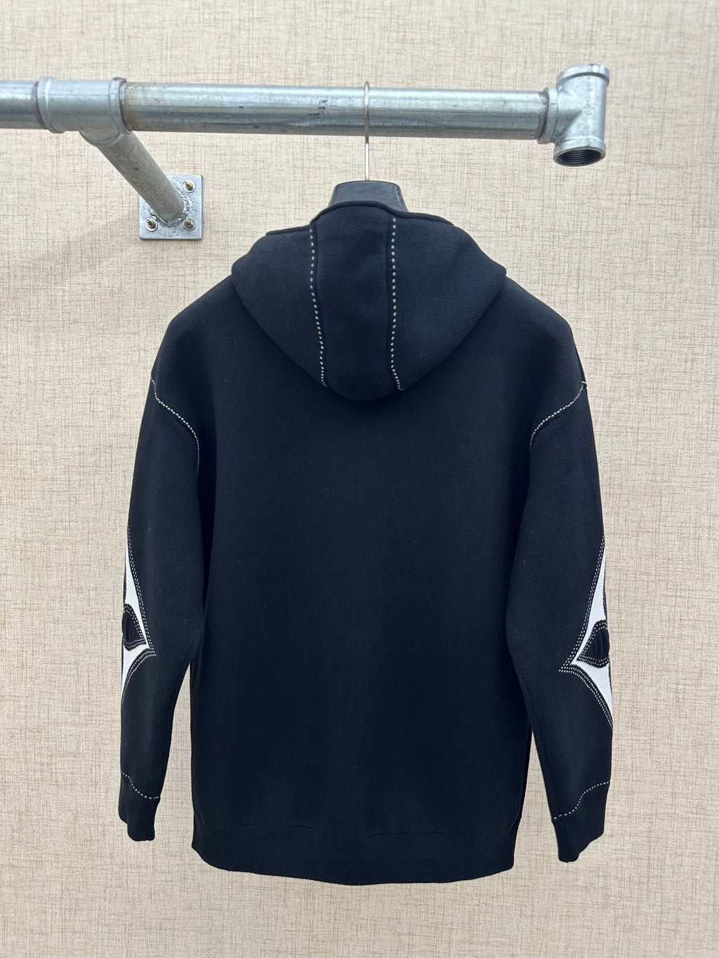 Back view zip-up hoodie with hood, dark knit, and contrast diamond sleeve graphic