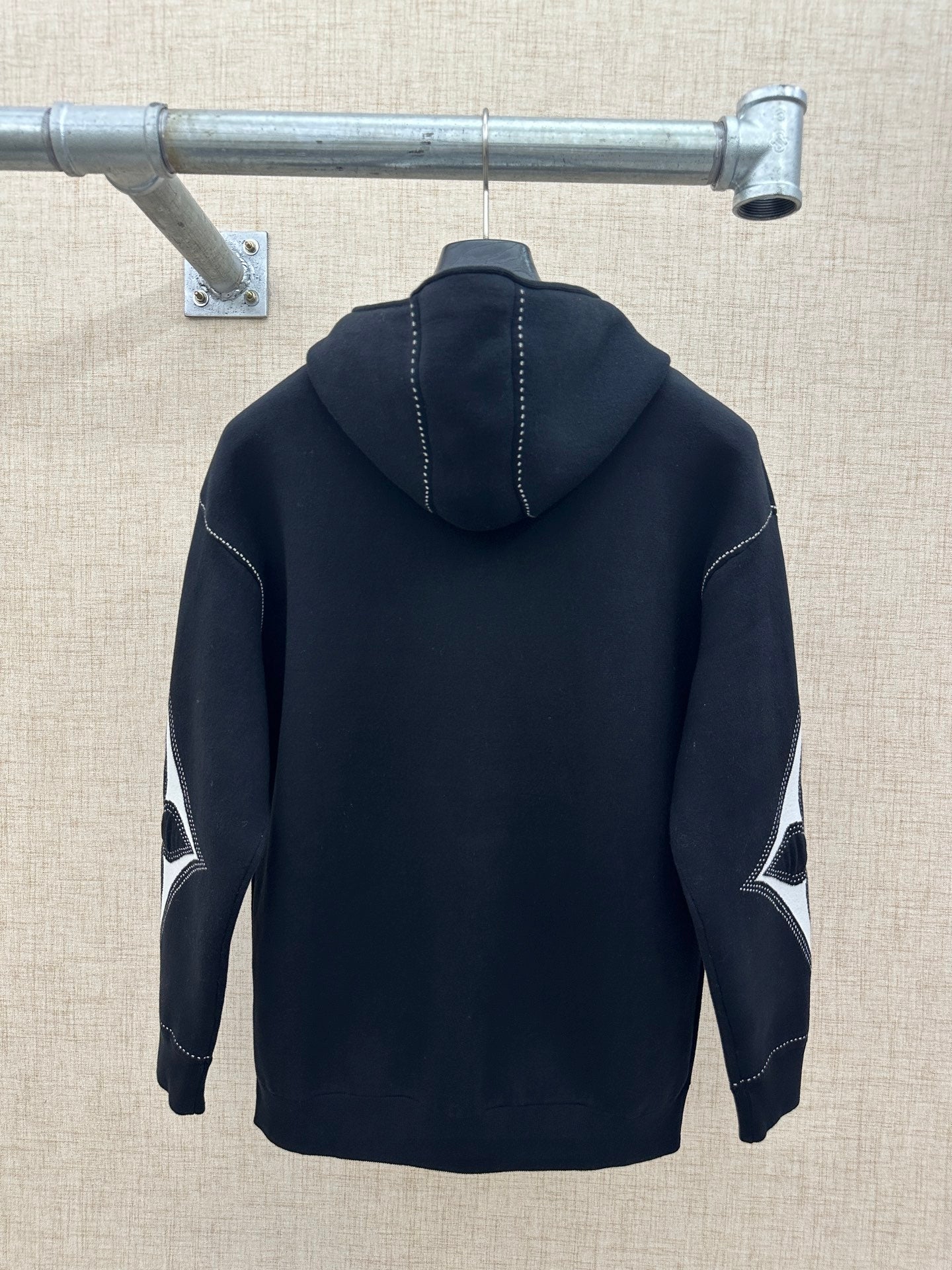 Back view zip-up hoodie with hood, dark knit, and contrast diamond sleeve graphic