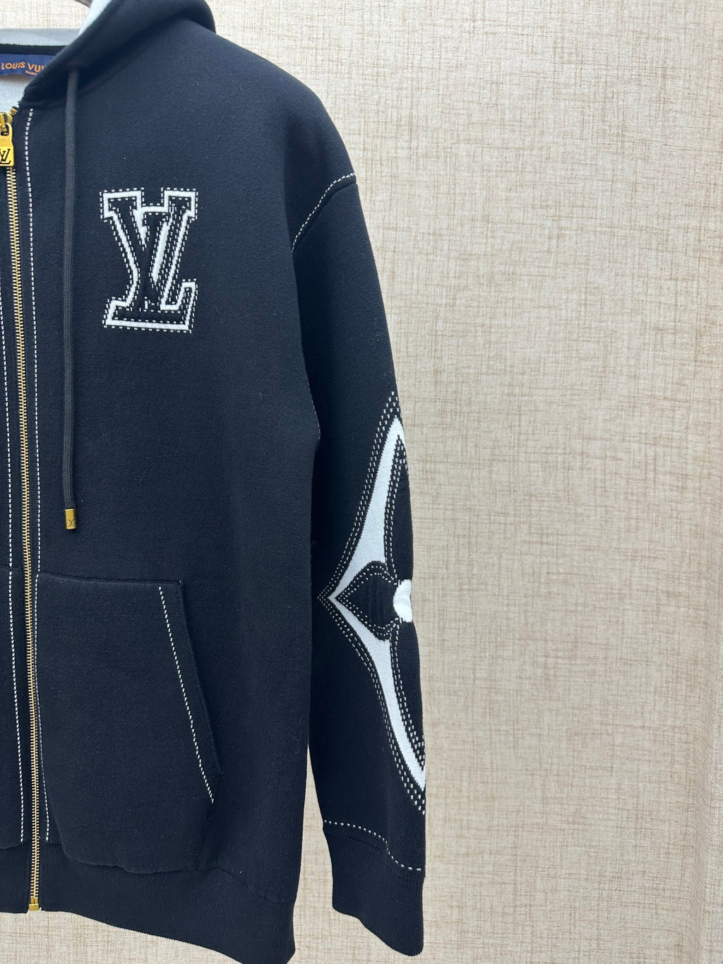 Side view zip-up hoodie with white LV-style logo and contrast diamond sleeve panel