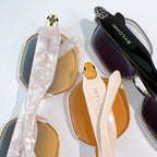 Gold-tone sunglasses with orange lenses and white temples next to dark-lens frames