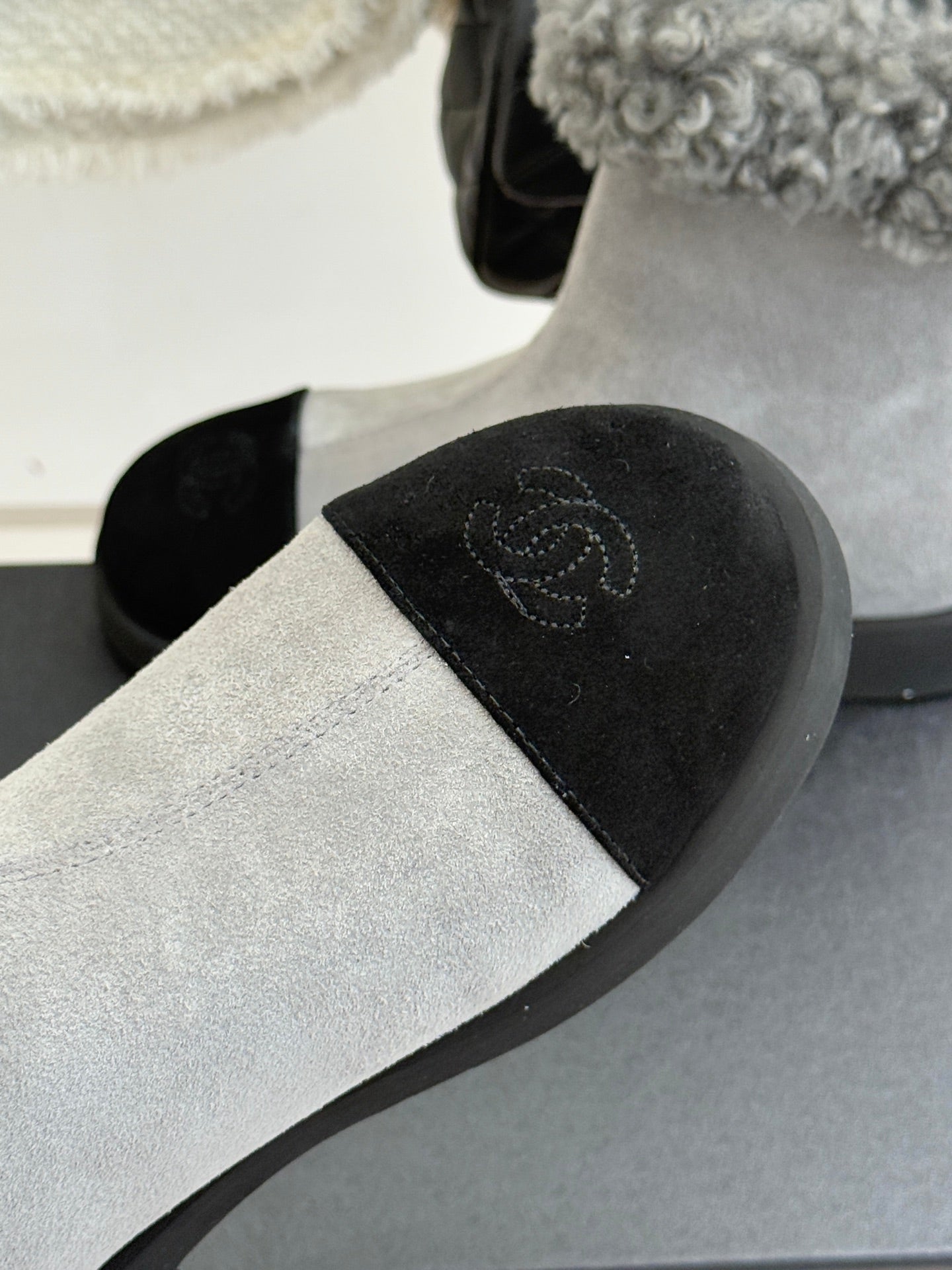 Light gray suede ankle boot with black side panel and subtle embroidered logo
