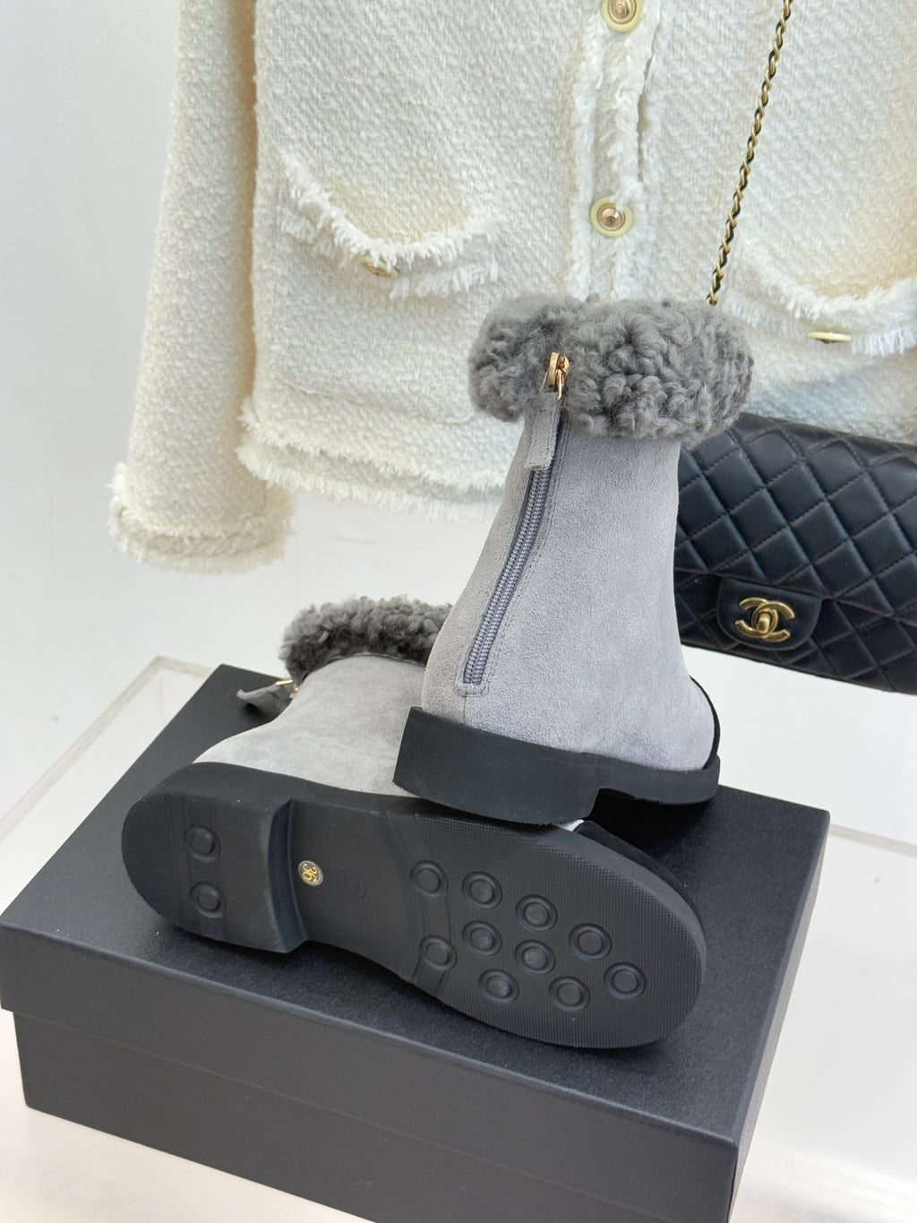 Light gray suede ankle boots with textured black rubber outsole and gold hardware