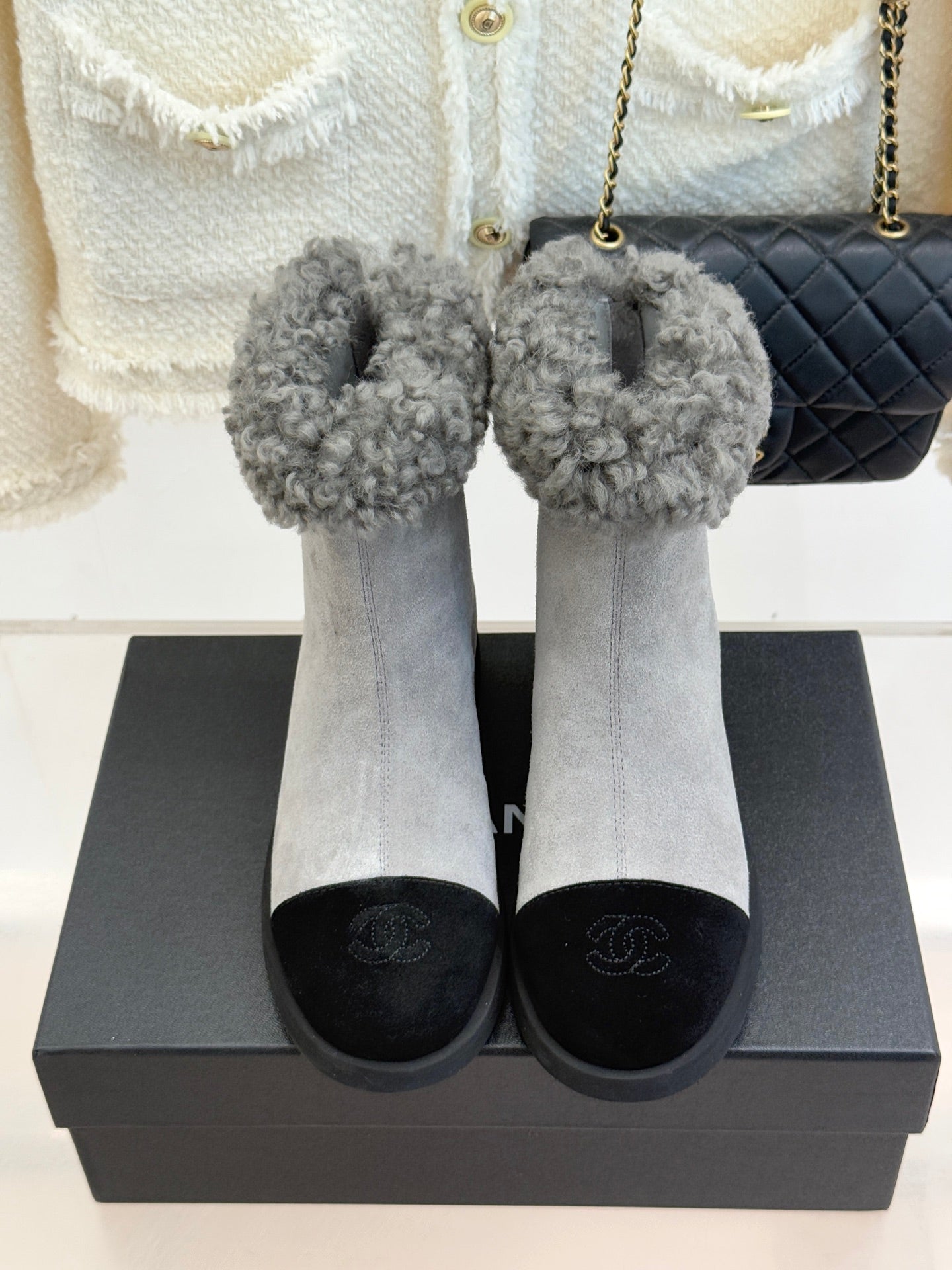 Pair of light gray suede ankle boots with gray shearling cuffs on black rubber soles