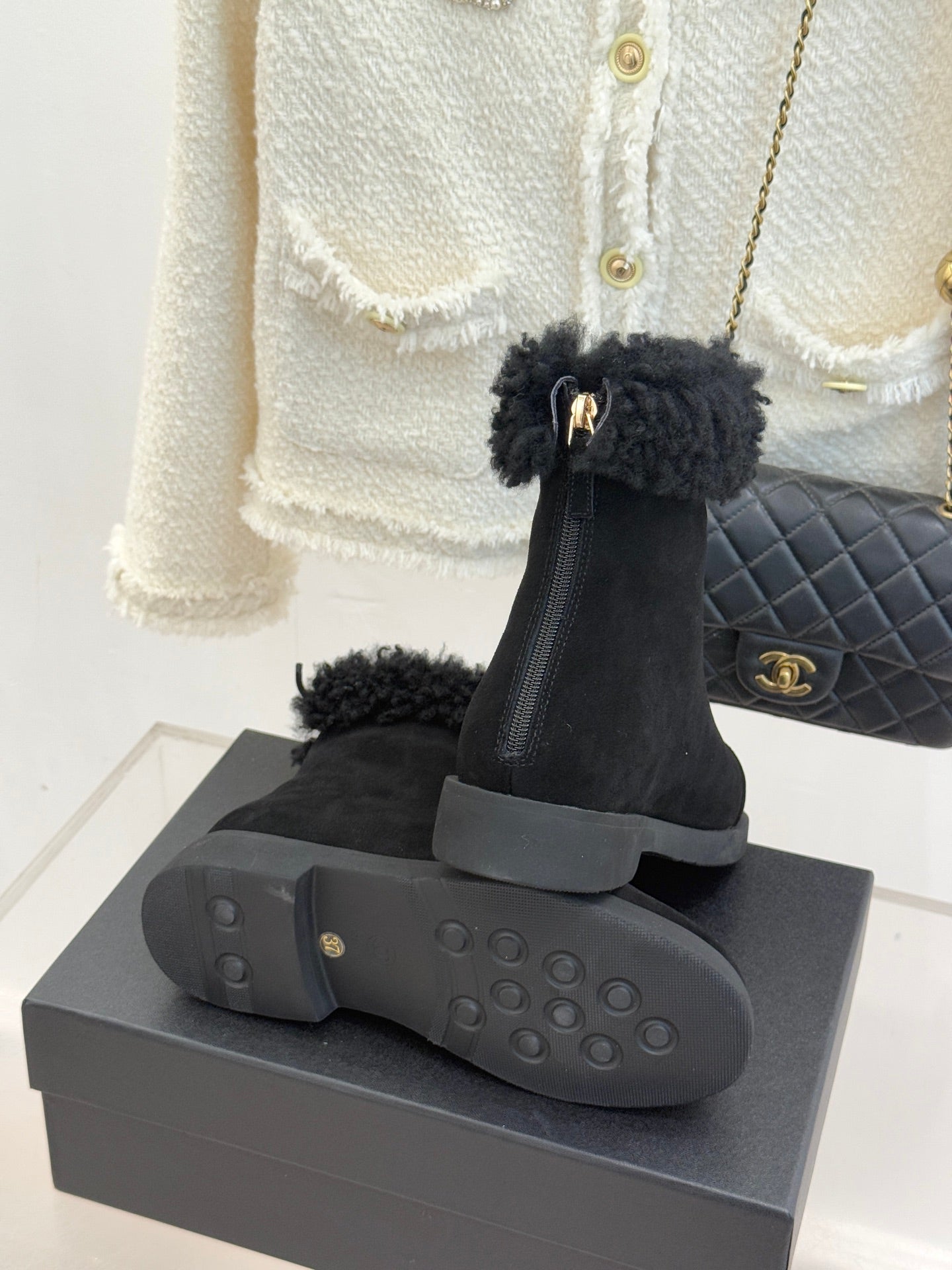 Black suede ankle boots with faux-fur cuffs on a display box