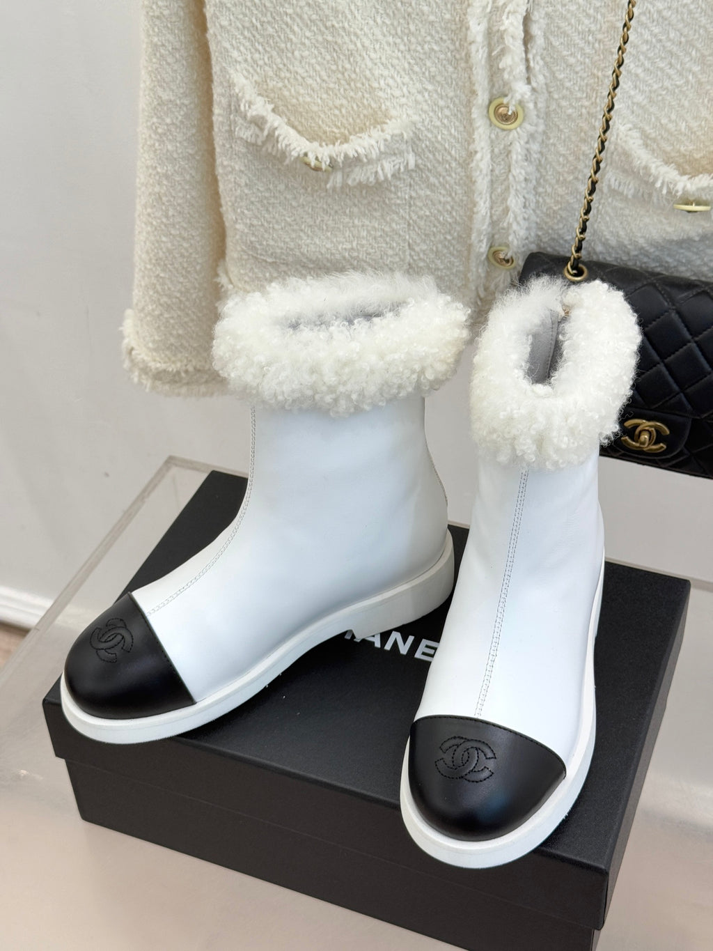 White women's ankle boots with black heel panel and shearling trim, slip-on