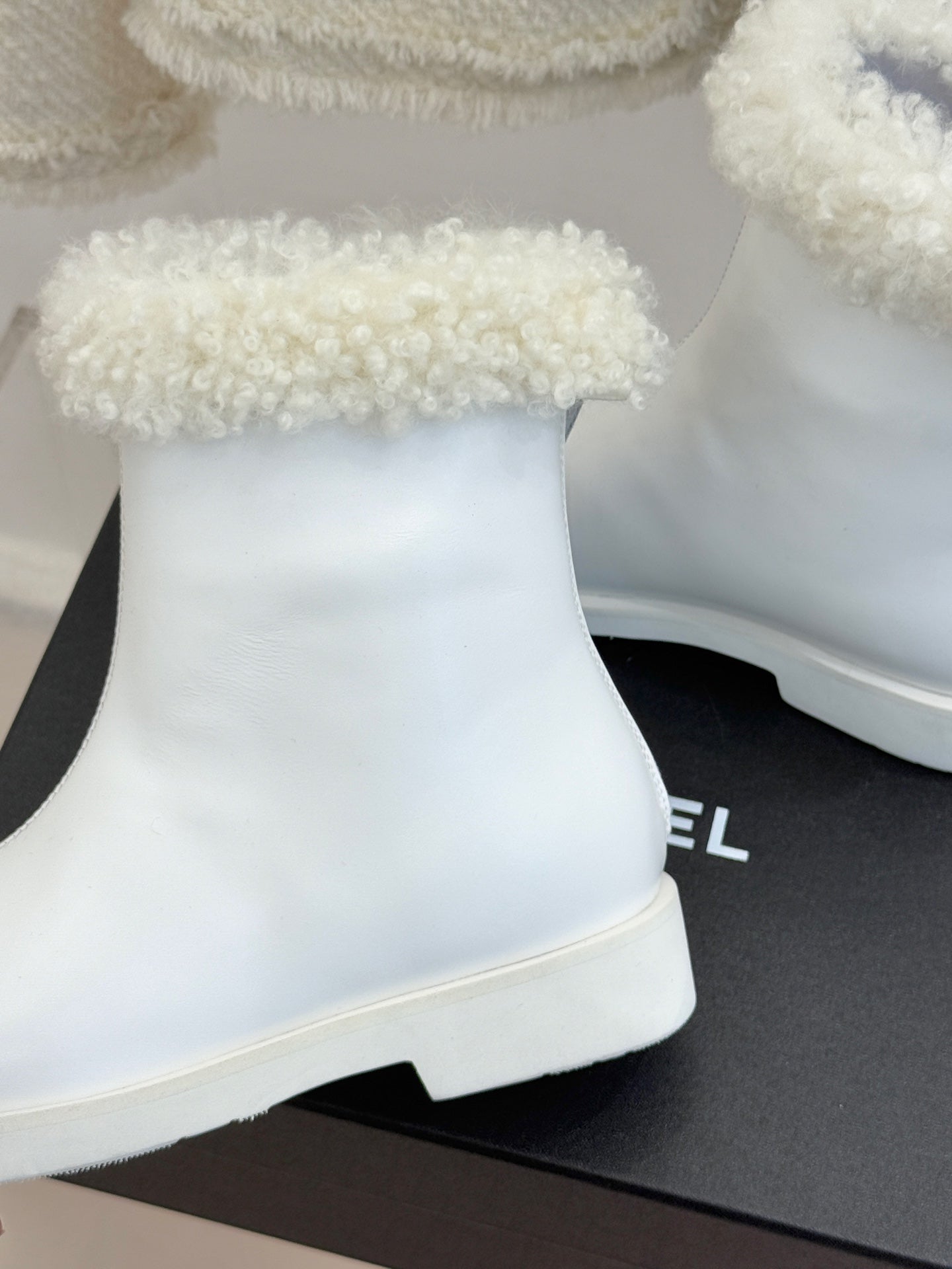 White women's ankle boot with black side insert and chunky rubber sole, close-up