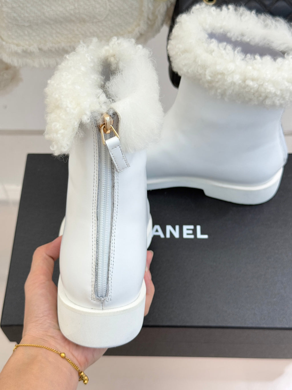 White women's ankle boot with side zipper and fluffy shearling cuff, heel view