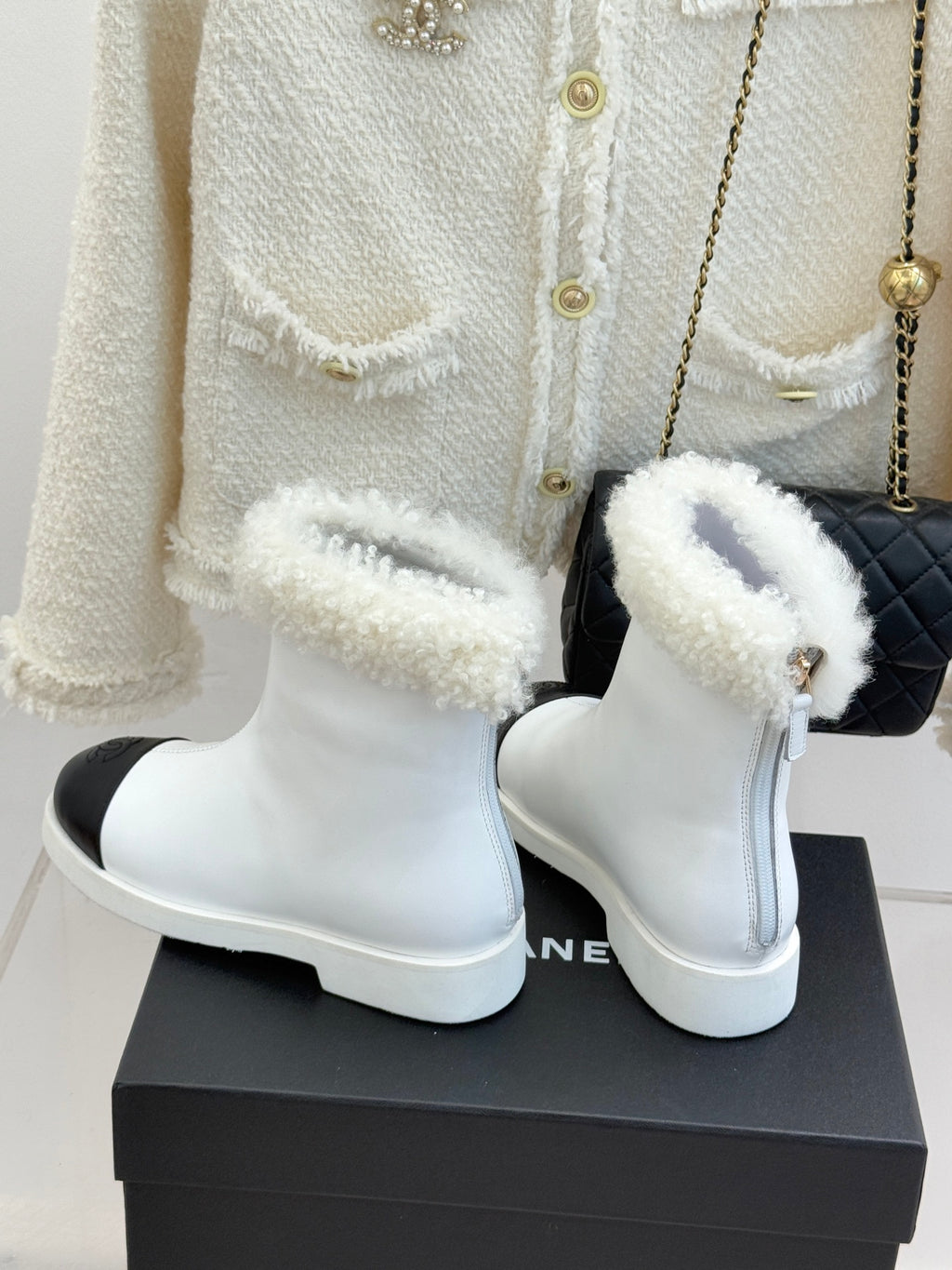 White women's ankle boots with black side panel and plush shearling cuffs, pair
