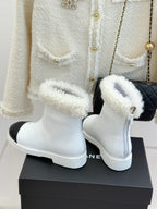White women's ankle boots with black side panel and plush shearling cuffs, pair