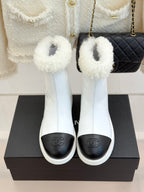Pair of white women's ankle boots with black toe and fuzzy shearling cuffs