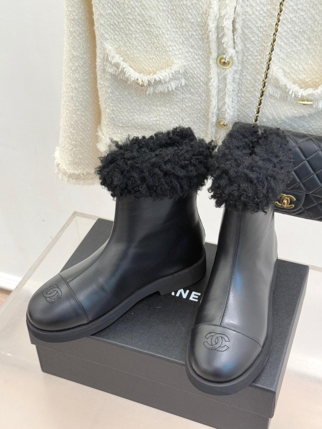 Black leather ankle boots with black faux-fur cuffs and side Chanel-style logo