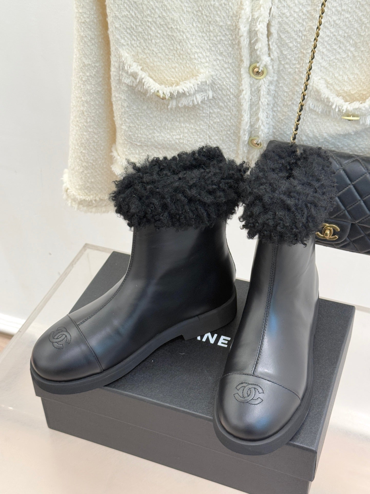 Black leather ankle boots with black faux-fur cuffs and side Chanel-style logo