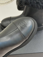 Close-up of black leather ankle boot with embossed logo and curved stitch line
