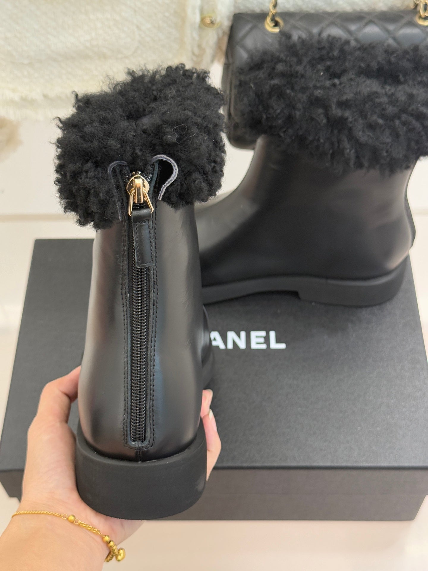 Black leather ankle boot with visible side zipper and black faux-fur cuff