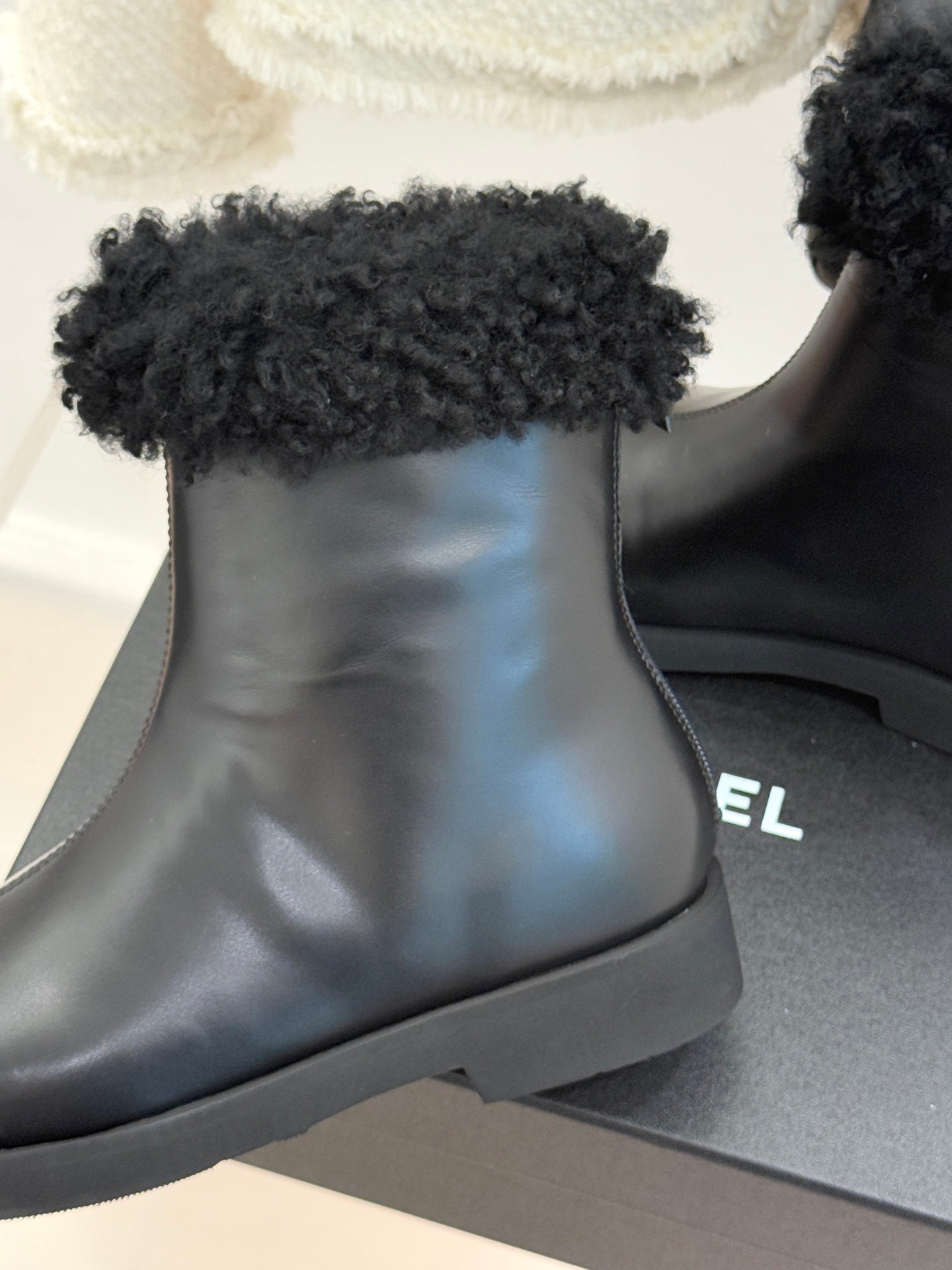 Close-up of black leather ankle boot with black faux-fur cuff and rounded toe