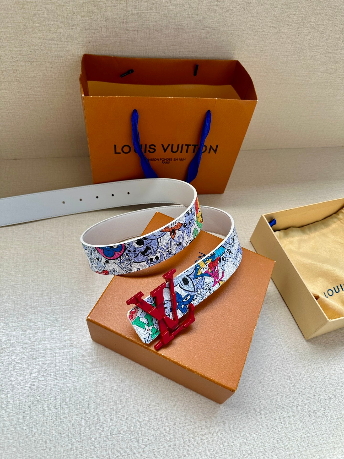 Printed belt with white strap and red LV buckle, colorful cartoon pattern