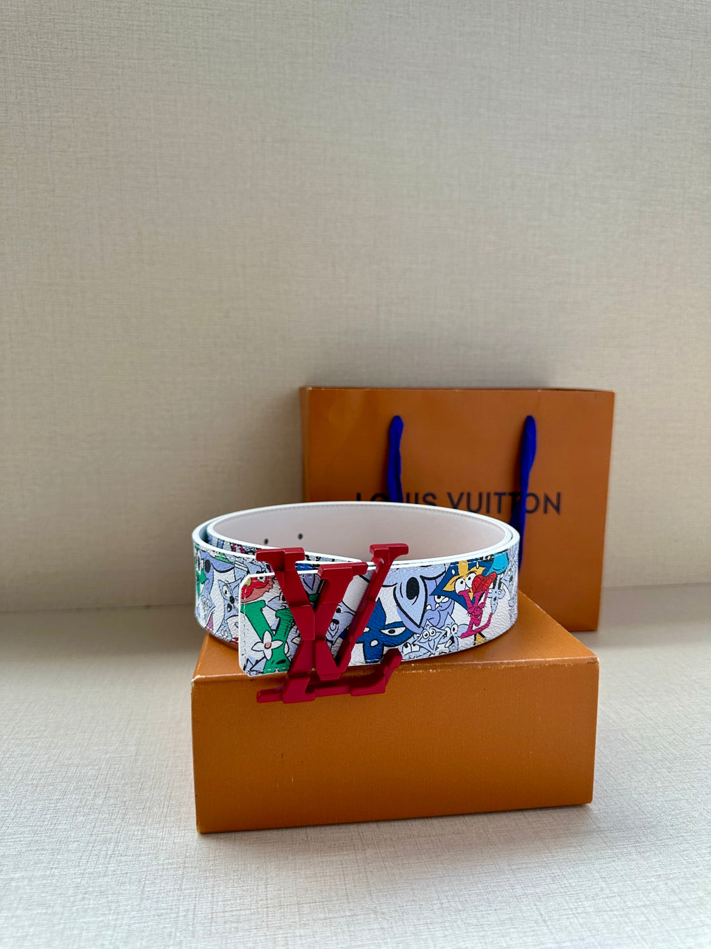 White graphic belt with large red LV buckle on a smooth strap