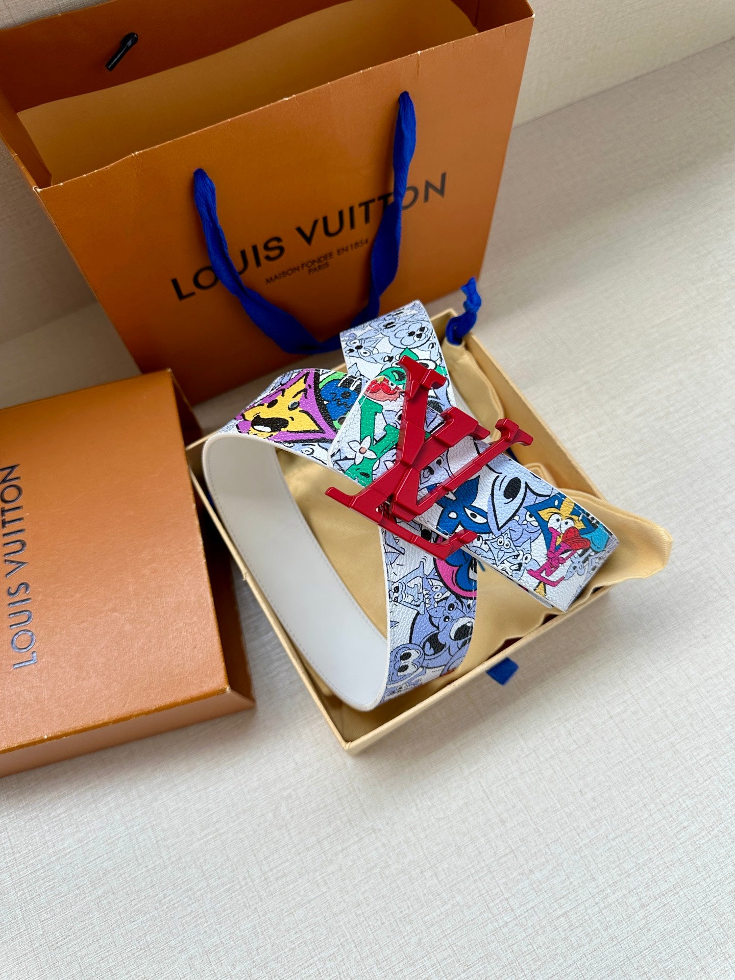 Printed Louis Vuitton belt with white strap and red LV buckle