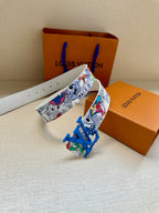 Louis Vuitton belt angled view: multicolor comic print strap and blue LV buckle