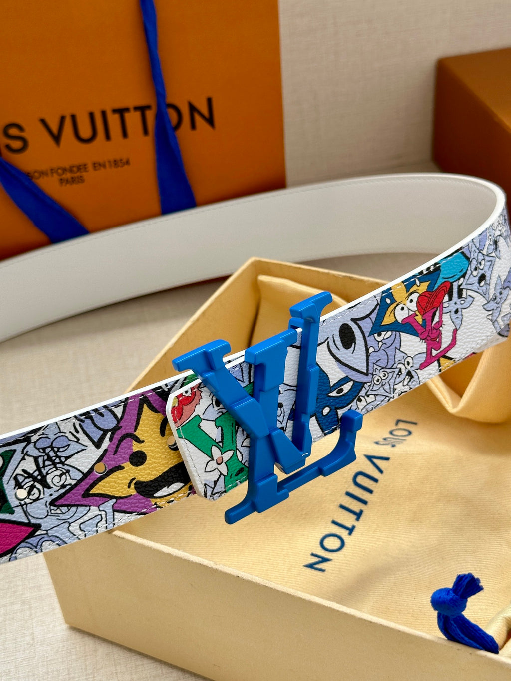 Louis Vuitton belt close-up: multicolor comic print strap with blue LV buckle
