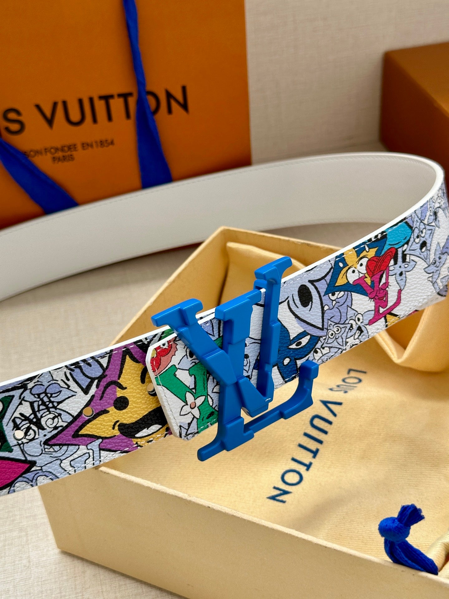 Louis Vuitton belt close-up: multicolor comic print strap with blue LV buckle