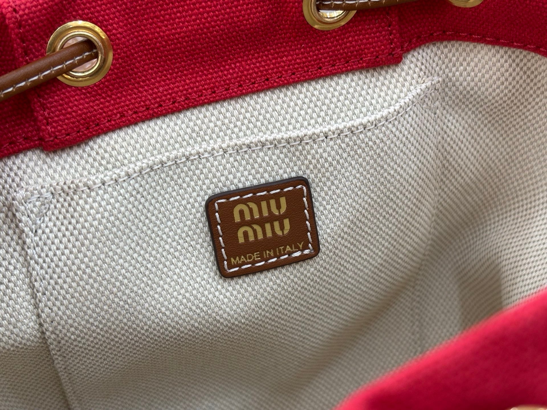 MiuMiu cream lining logo patch reading 'Miu Miu Made in Italy'