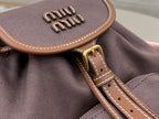 MiuMiu dark gray mini bag flap close-up with MiuMiu logo and brown edge trim