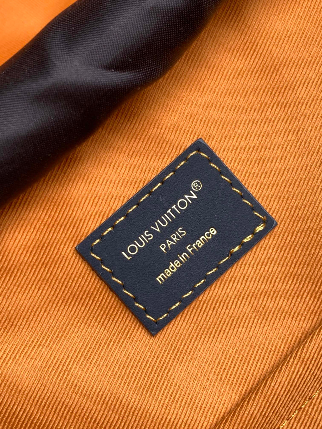 Louis Vuitton made in France leather label on orange fabric lining