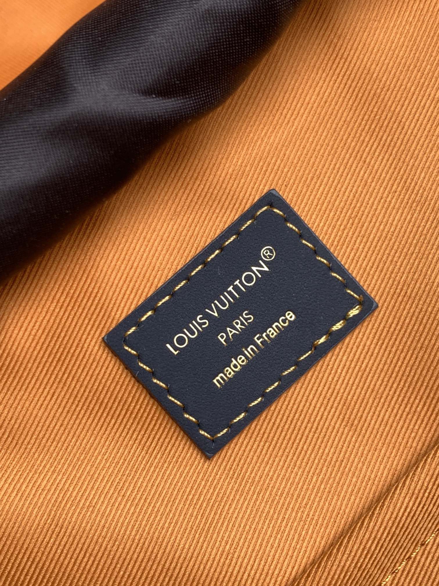 Louis Vuitton made in France leather label on orange fabric lining