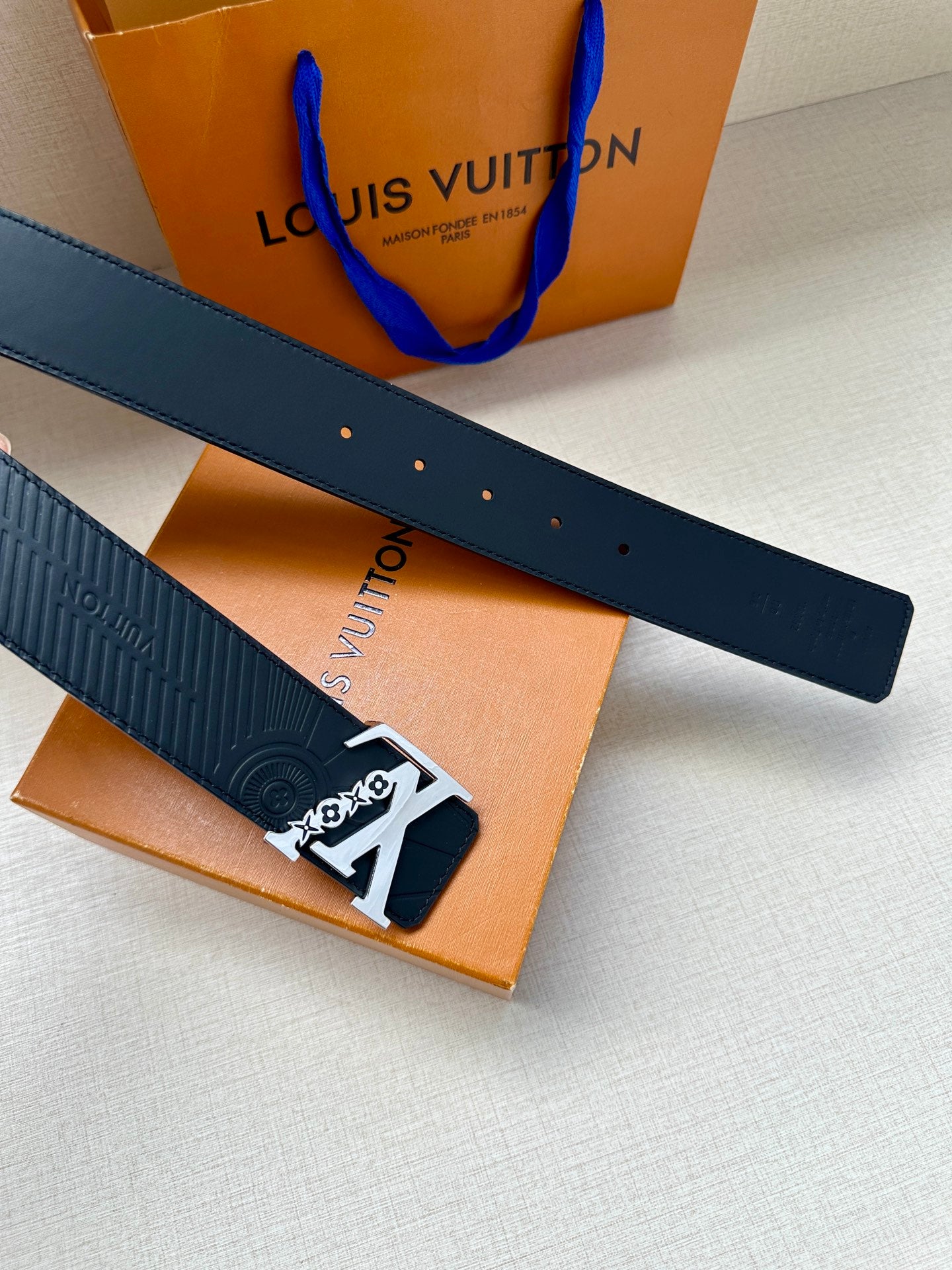 Louis Vuitton belt close-up: dark blue strap with perforation holes and gold-tone buckle