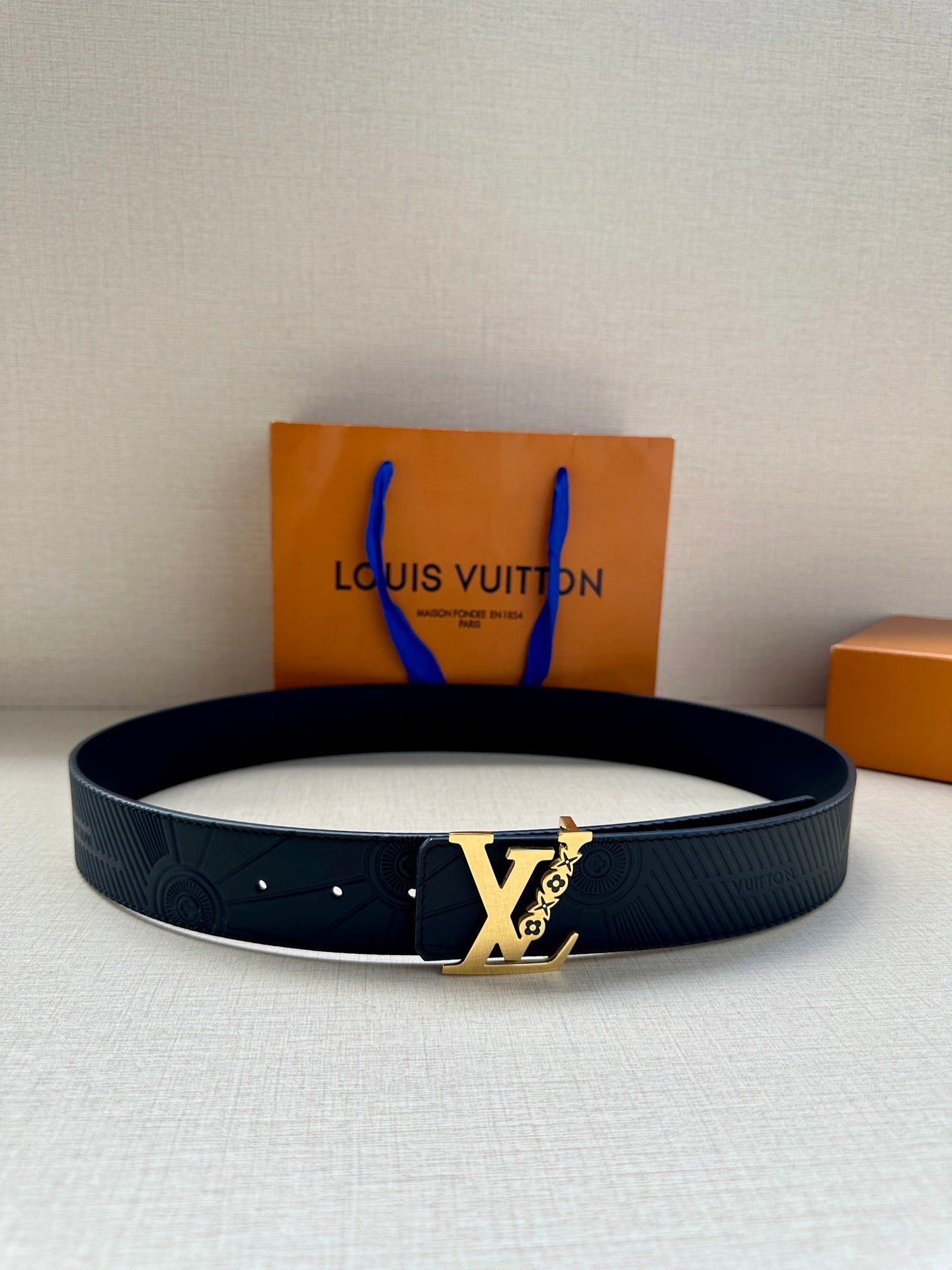 Louis Vuitton monogram belt with dark blue strap and gold-tone buckle on display