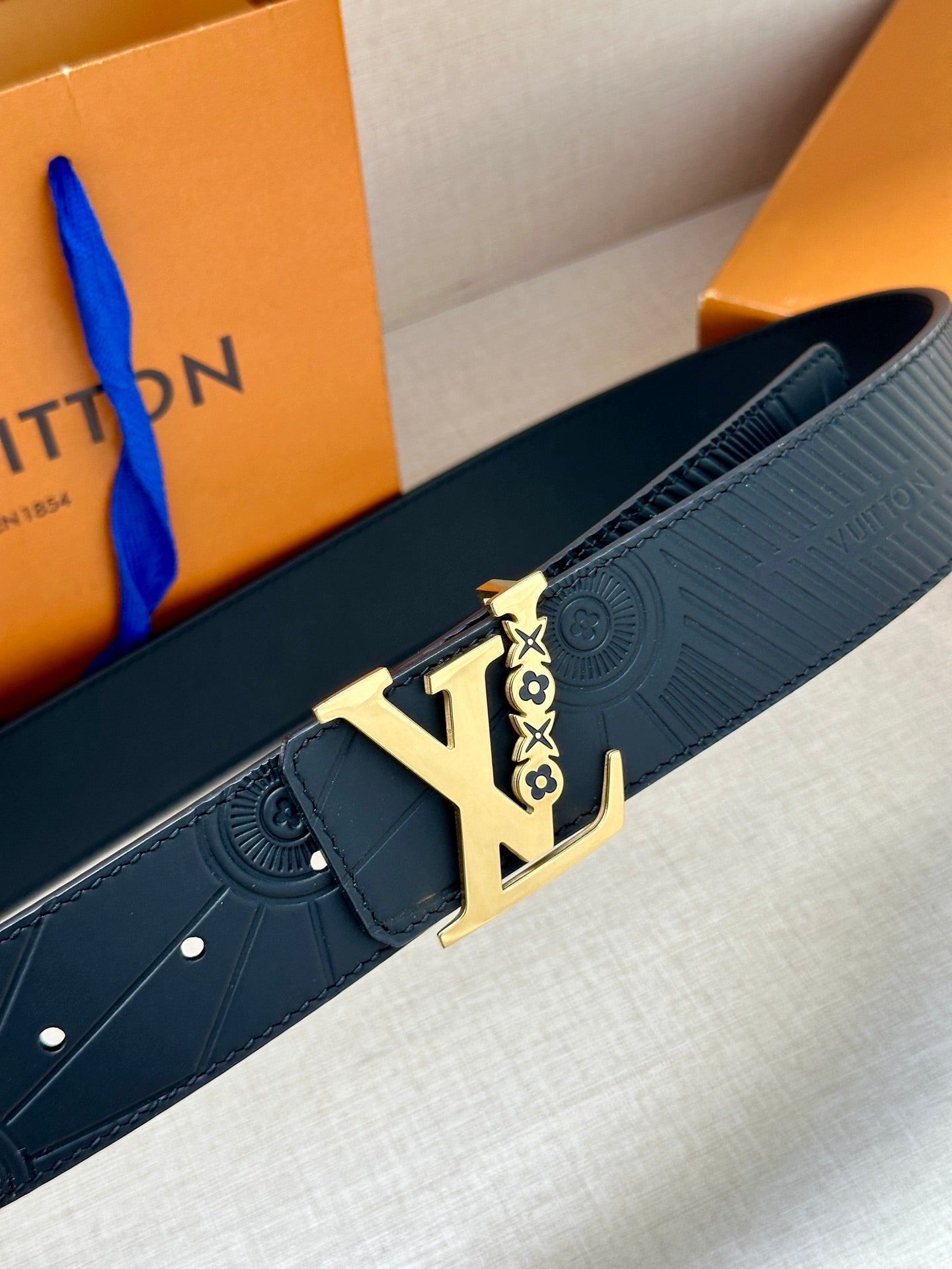 Louis Vuitton belt close-up: dark blue embossed strap with gold-tone buckle hardware