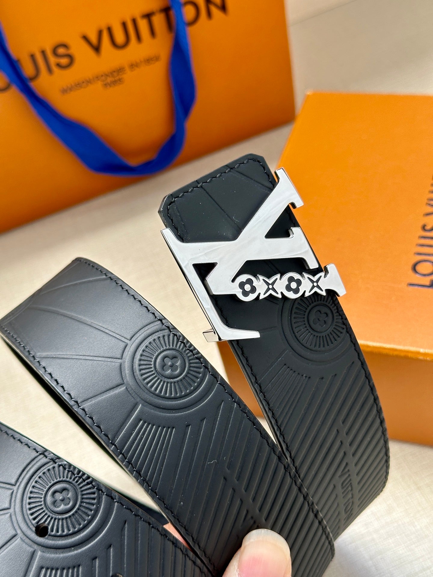 Louis Vuitton belt close-up: dark blue embossed strap with large logo buckle