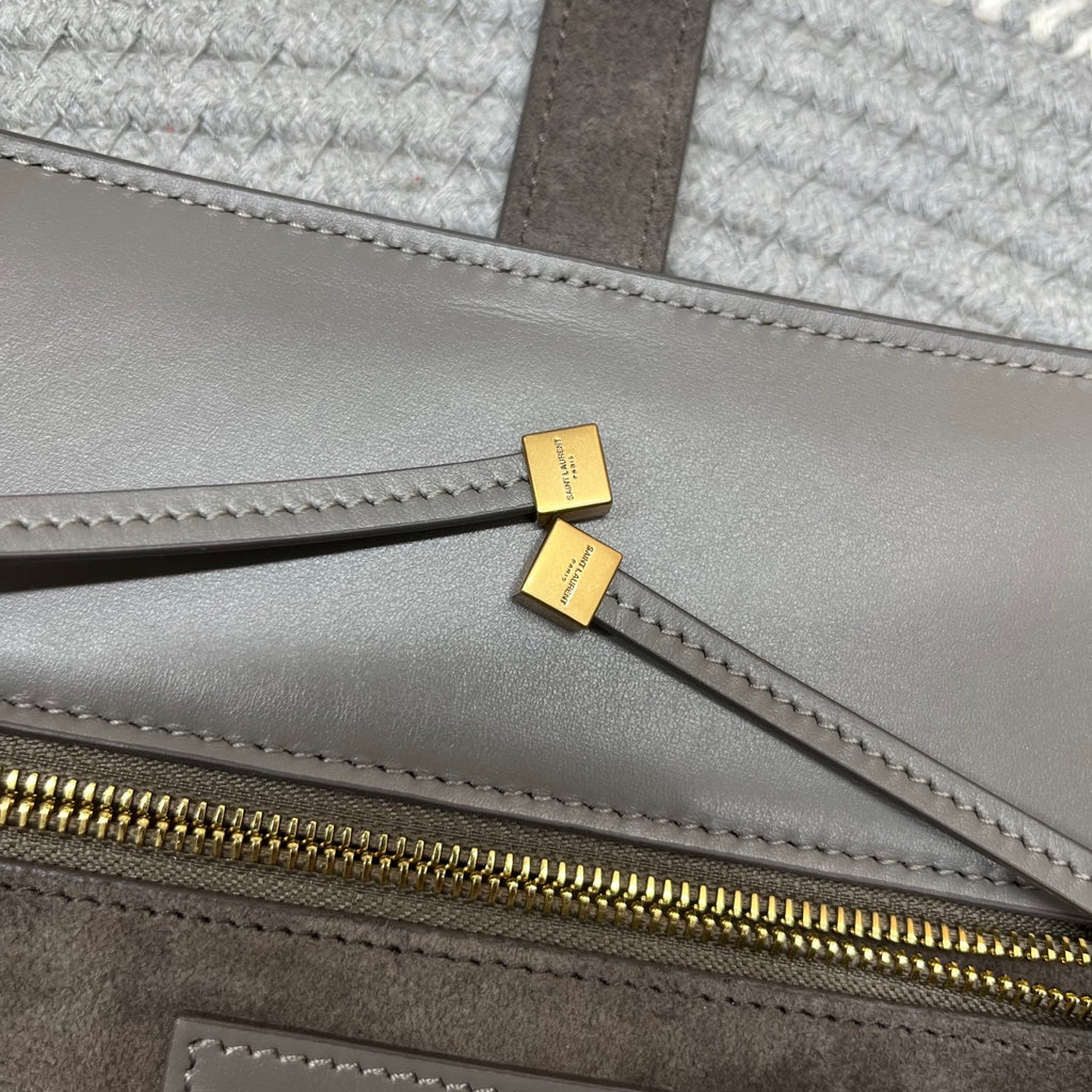 Gray leather tote with gold zipper track and small gold logo hardware tabs